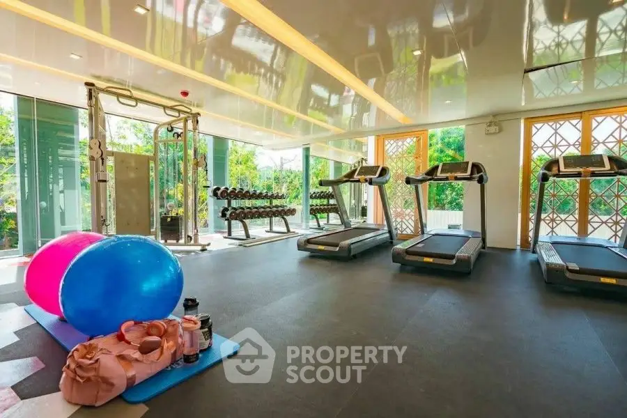 Luxurious gym with modern equipment and scenic garden views in upscale property.