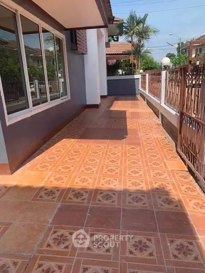 Spacious tiled balcony with decorative railing and garden view in a modern home.