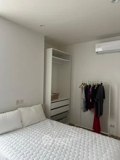 Cozy bedroom with minimalist design, featuring a bed, open wardrobe, and air conditioning.