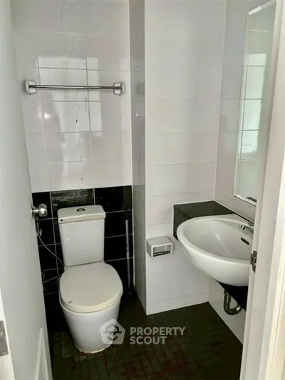 Compact bathroom with modern fixtures and tiled walls, featuring a toilet and sink.