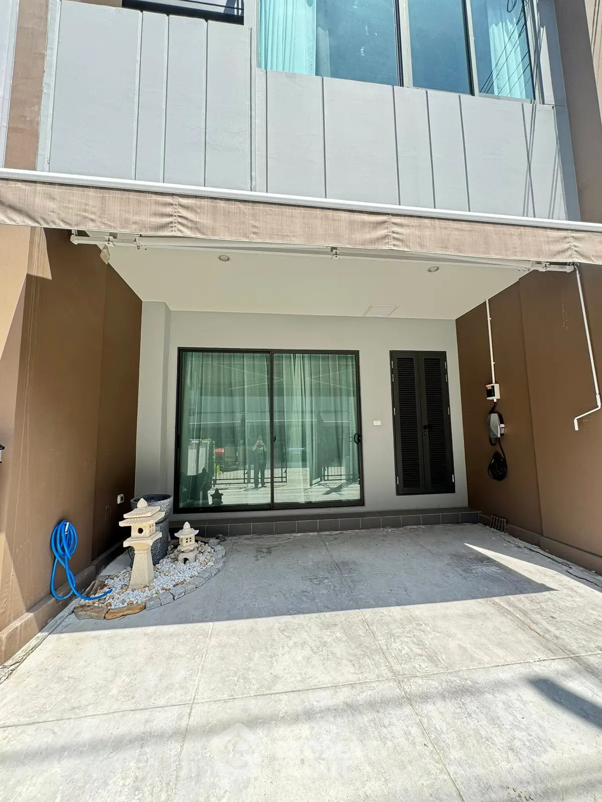 Modern townhouse exterior with sliding glass doors and minimalist garden decor.