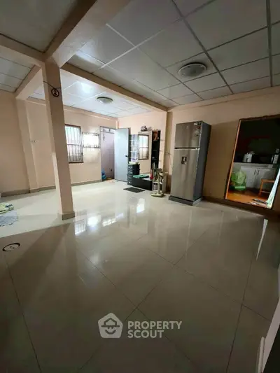Spacious open-plan living area with modern fridge and tiled flooring, ideal for family gatherings.