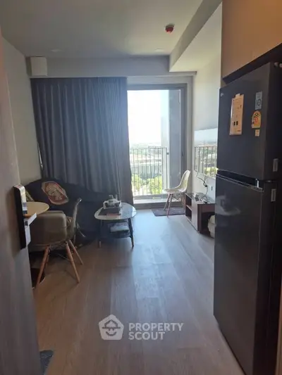 Modern apartment living room with balcony view and sleek kitchen appliances.