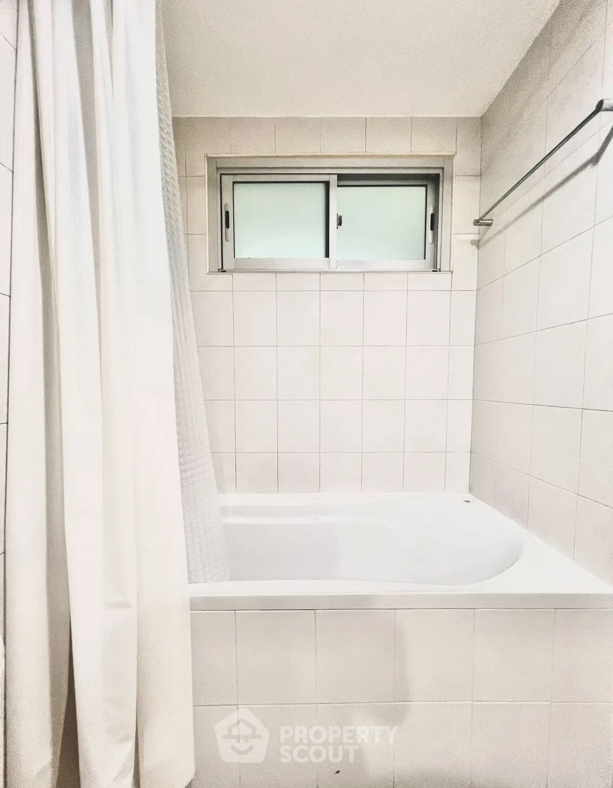 Bright bathroom with bathtub and window, perfect for relaxation.