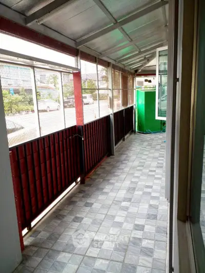 Spacious enclosed balcony with tiled flooring and street view, perfect for relaxation.