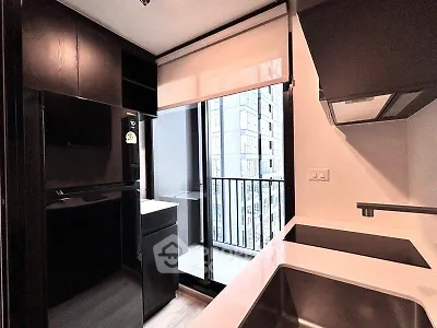 Modern kitchen with sleek black cabinetry and balcony view in urban apartment