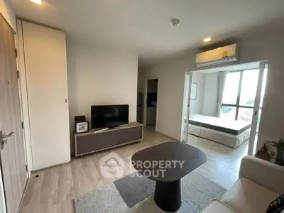Modern living room with open view to bedroom, featuring sleek furniture and natural light.