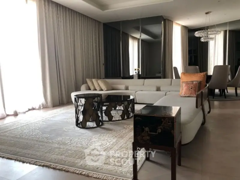 Luxurious living room with elegant decor, featuring a plush sectional sofa, chic coffee table, and exquisite chandelier.