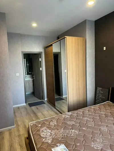 Modern bedroom with wooden flooring and mirrored wardrobe in stylish apartment.