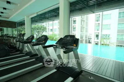 Modern gym with treadmills overlooking a luxurious pool in a high-end residential building.