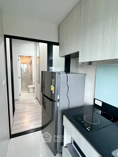 Modern kitchen with sleek appliances and view into a stylish bathroom