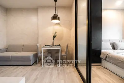 Modern studio apartment with cozy living area and stylish bedroom separated by glass partition.
