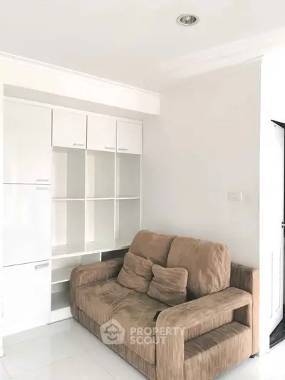 Cozy living room with modern beige sofa and white built-in shelves, perfect for relaxation.