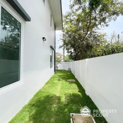 Charming side garden with lush green lawn and modern white fence