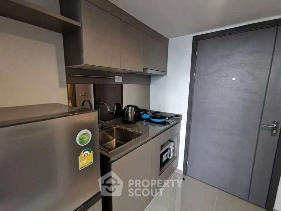 Modern compact kitchen with sleek cabinetry and built-in appliances in a stylish apartment.