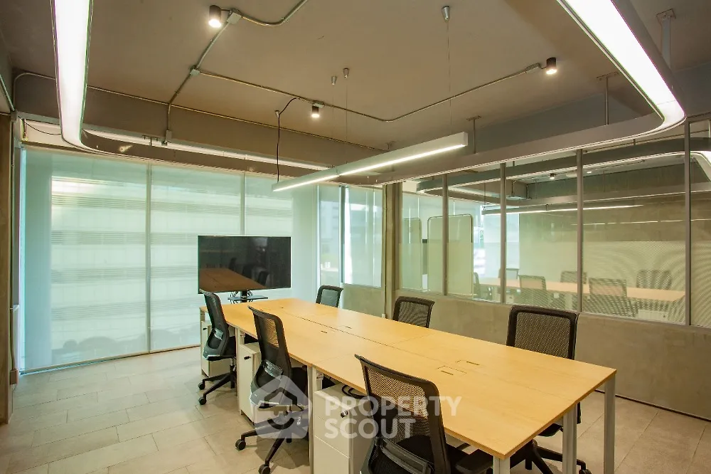 Modern office space with sleek design and ample natural light, featuring a long conference table and ergonomic chairs.