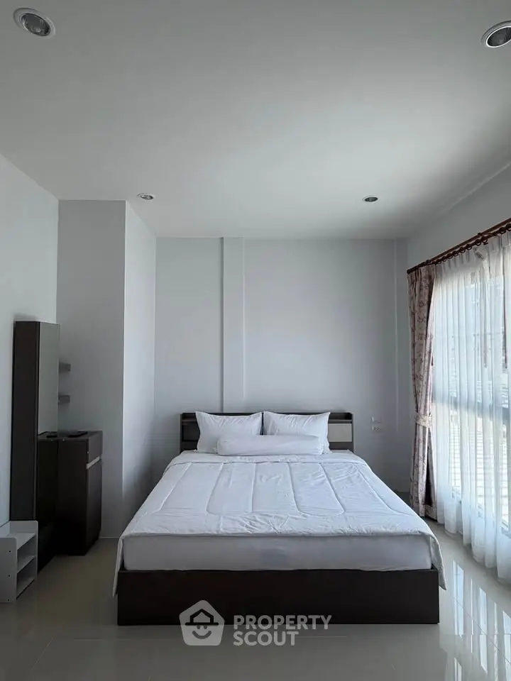 Spacious bedroom with large windows and modern minimalist decor, perfect for natural light lovers.