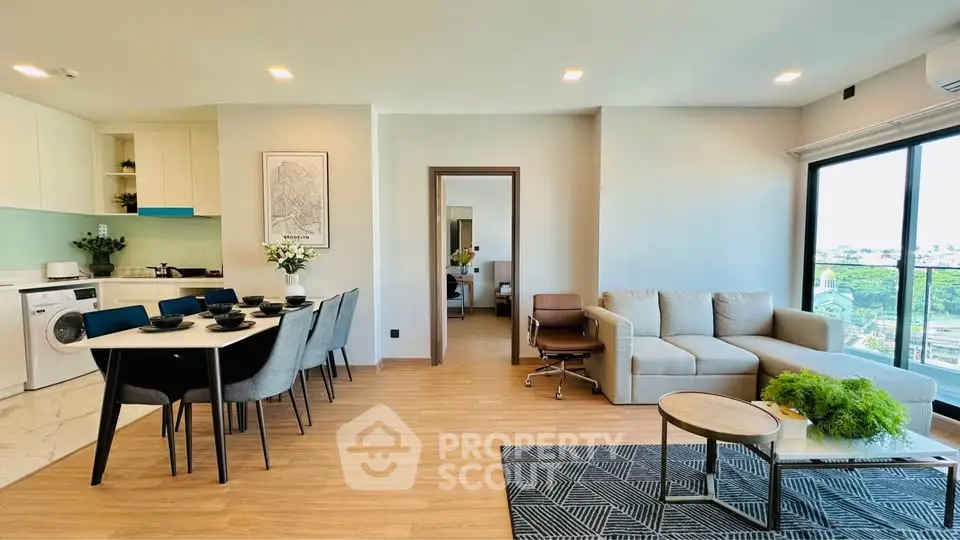 Spacious modern living room with open kitchen and dining area, featuring elegant decor and large windows with city view.