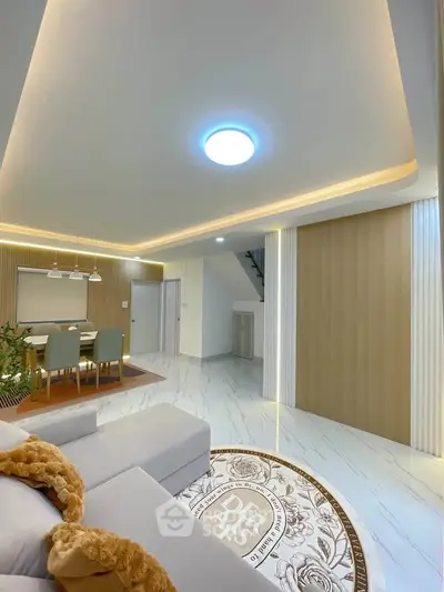 Modern living room with elegant lighting and stylish decor, featuring a cozy dining area and sleek flooring.