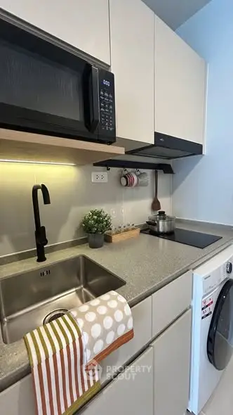 Modern kitchen with sleek cabinets, built-in microwave, and washing machine, perfect for urban living.