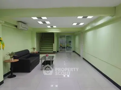 Spacious modern living room with sleek black sofa and glass coffee table, ideal for relaxation.