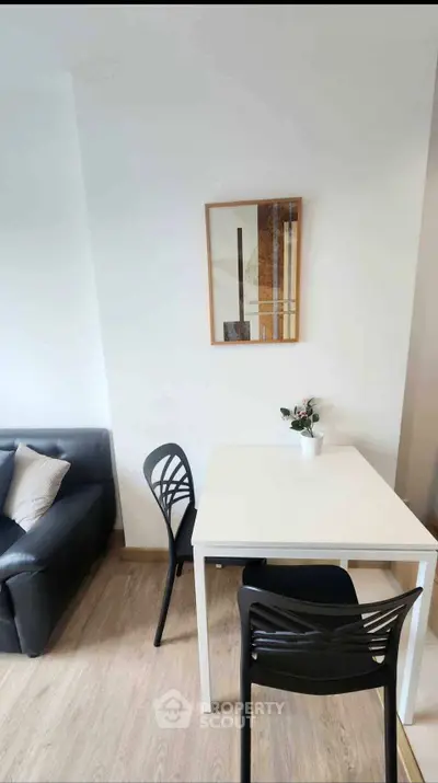 Modern living room with sleek black sofa and minimalist dining area, perfect for urban living.