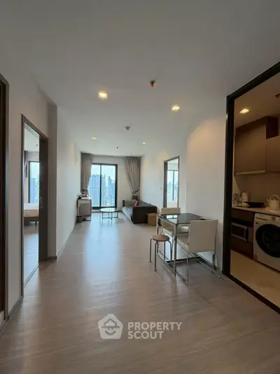 Spacious modern apartment with open living area and city view, featuring sleek kitchen and dining space.