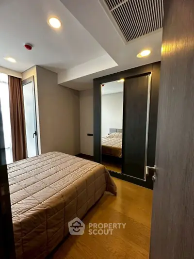 Modern bedroom with cozy bedding and mirrored wardrobe in a stylish apartment.