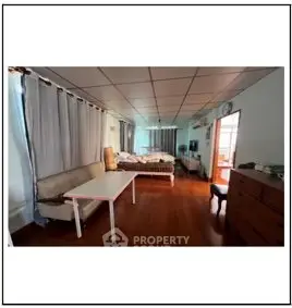 Spacious bedroom with wooden flooring and natural light