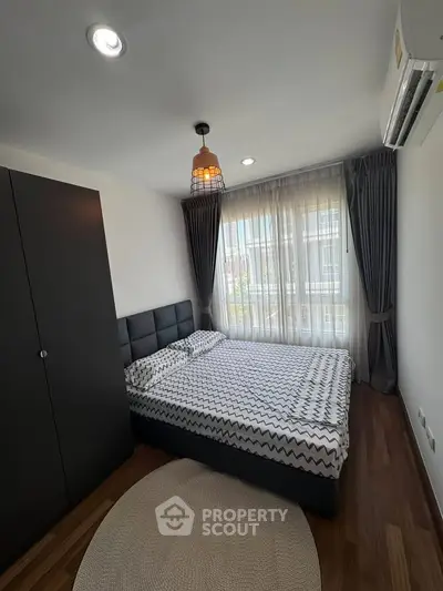 Modern bedroom with stylish decor and large window offering natural light