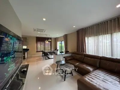 Spacious modern living room with leather sofa and dining area, perfect for family gatherings.