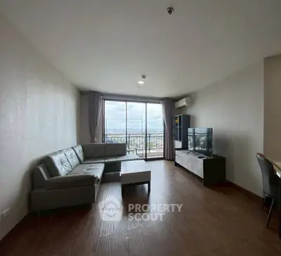 Spacious living room with large windows and city view, featuring modern furniture and sleek flooring.