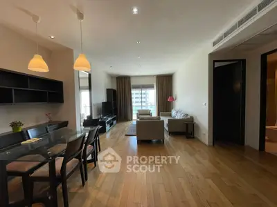 Spacious living room with modern furniture and wooden flooring in a well-lit apartment.