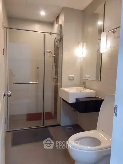 Modern bathroom with glass shower enclosure and sleek fixtures in a contemporary apartment.