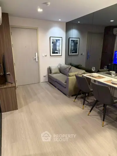 Modern living room with sleek furniture and mirrored wall enhancing space.