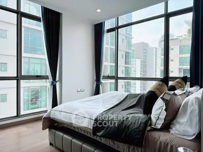 Luxurious bedroom with large windows offering stunning city views in a modern apartment.
