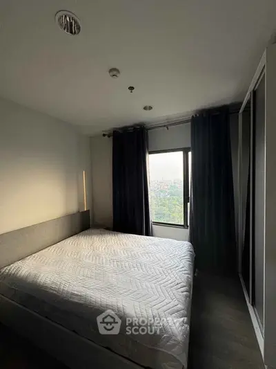 Cozy bedroom with large window offering stunning city view, featuring modern decor and ample natural light.