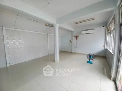 Spacious empty room with tiled floor and air conditioning, ideal for customization.