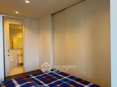 Modern bedroom with ensuite bathroom and stylish plaid bedding in a contemporary apartment.