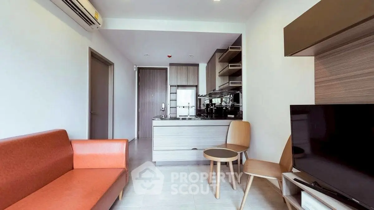 Modern living room with open kitchen, stylish furniture, and air conditioning.