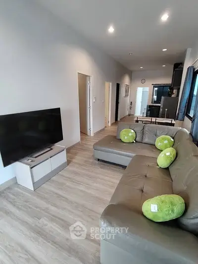 Modern living room with sleek furniture and open layout, featuring a large TV and stylish decor.