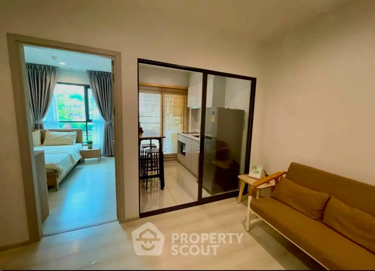 Modern apartment interior with cozy living room and stylish kitchen, featuring a view into a bright bedroom.