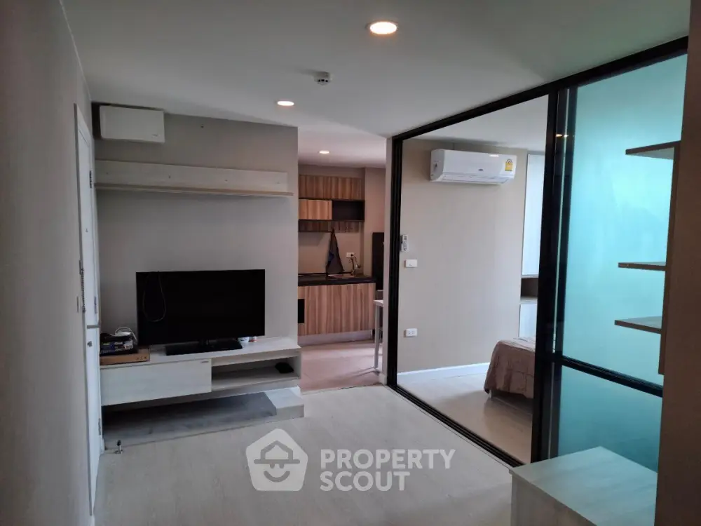 Modern open-plan living room with sleek kitchen and glass partition