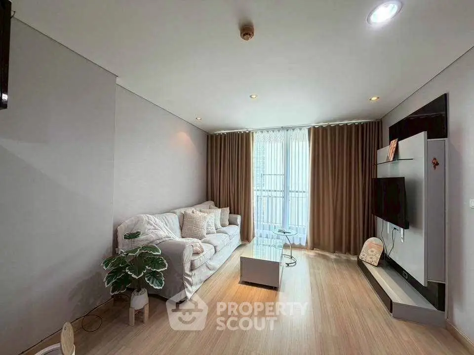 Modern living room with cozy sofa, stylish decor, and natural light from large window.