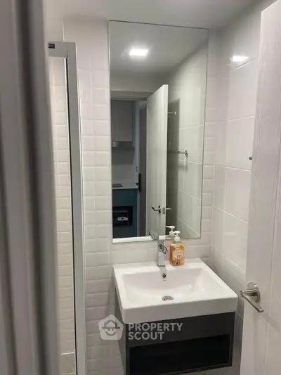 Modern bathroom with sleek sink and large mirror in compact space.