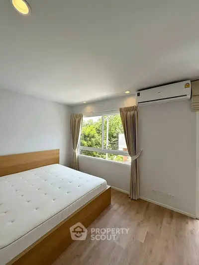 Bright bedroom with large window and modern air conditioning unit, featuring a comfortable bed and elegant curtains.