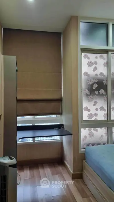 Cozy bedroom with wooden flooring and floral window design, perfect for a serene living experience.