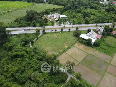 Expansive aerial view of lush green land with road access, ideal for development.