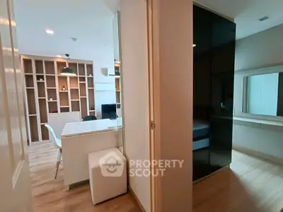 Modern apartment interior with open living and dining area, featuring sleek furniture and stylish shelving.