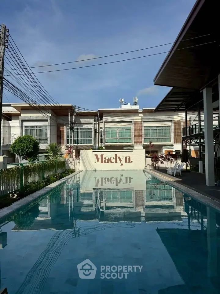 Stunning residential complex with a pristine swimming pool and modern architecture under a clear blue sky.